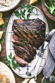 a steak on a plate with parsley garnish next to it and a knife