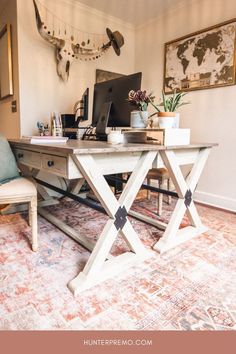 a desk with a chair and computer on it in front of a wall mounted deer head