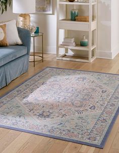 a living room with a blue couch and rug on the floor next to a book shelf