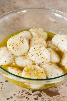 some kind of food that is in a bowl on a table with olive oil and seasoning