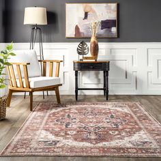 a living room with two chairs and a rug on the floor in front of a painting