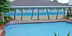 an outdoor swimming pool with palm trees and the ocean in the backgroung