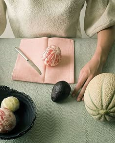 an avocado, melon and other fruit are on a green tablecloth