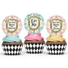 three cupcakes with different colored frosting and designs on them, one has a plate that says eat me