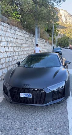 a black sports car parked next to a brick wall