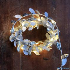 a lighted wreath on a wooden surface with leaves and branches attached to the front of it