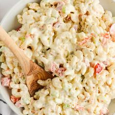 a white bowl filled with macaroni salad and a wooden spoon