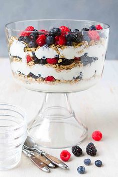 a glass bowl filled with fruit and yogurt on top of a white table