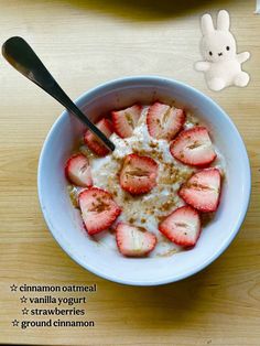 a bowl filled with yogurt and strawberries on top of a table next to a stuffed animal