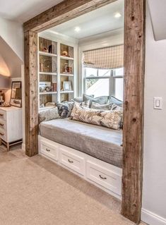 a large window seat in the middle of a living room with built - in bookshelves