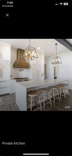 an image of a kitchen with white cabinets and counter tops in the center is a large island that has stools on it