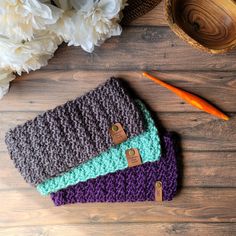 three crocheted purses sitting on top of a wooden table next to flowers