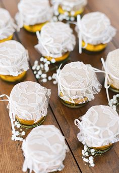 small jars filled with baby's breath flowers on top of a wooden table covered in lace