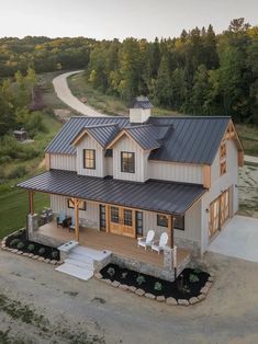 an aerial view of a house with a metal roof and two white chairs on the front porch