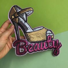 a hand holding up a sticker with the word beauty on it and a high heel shoe