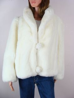 Fabulous vintage Donnybrook white faux faux plush jacket from the 80s.  Features a fold over shawl style collar with two faux fur pom pom style buttons with elastic loop closures down center front.  Has long sleeves and a straight silhouette with 5" front side pockets.  Made of a plush white faux fur material and is fully lined with a satiny cream colored woven material.  Freshly laundered and ready to wear. Label: "Donnybrook".  Made in U.S.A. Fiber Content: No label present, but is a faux fur. Stamped Size: No label present, but seems as though it would best fit a size small or medium.  Please see the measurements listed at the end of the description to ensure a proper fit.   Condition: In good vintage condition, but does have light general wear, mainly that the elastic loop closures are Classic White Long Sleeve Fur Coat, Classic White Fur Coat For Winter, Vintage White Winter Outerwear, Pom Pom Fashion, White Faux Fur Coat, Plush Jacket, Shawl Style, Faux Fur Material, White Faux Fur