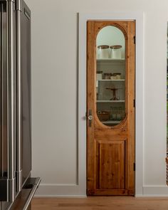 a wooden door in a kitchen next to a refrigerator