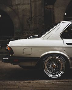 an old white car parked in front of a building