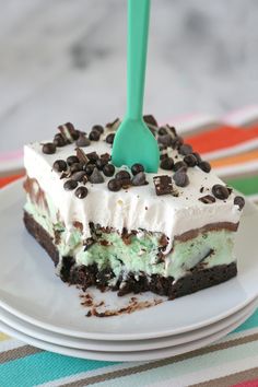 a piece of ice cream cake on a plate with a green fork in the middle