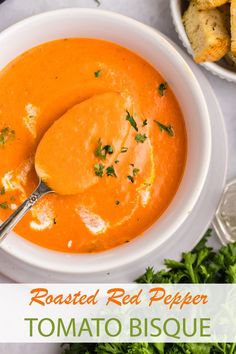 a bowl of roasted red pepper tomato biscuit soup with a spoon in it and garnished with parsley