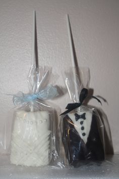 two wedding cake pops wrapped in cellophane and sitting on a shelf next to each other