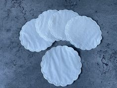 four white doily sitting on top of a cement floor