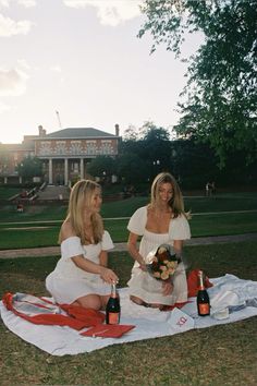 two women sitting on a blanket with bottles of wine