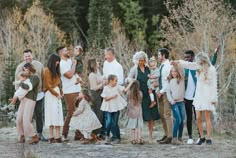 a group of people standing next to each other in front of some trees and bushes