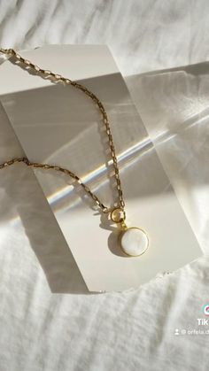 a necklace with a pearl on it sitting on top of a white sheet