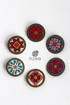 six beaded buttons with different colors and designs on the front, sitting in a circle