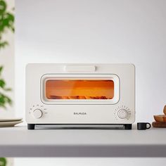 a white toaster oven sitting on top of a counter next to a plate with bread