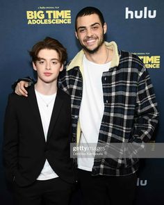 two young men standing next to each other in front of a blue background at the big time