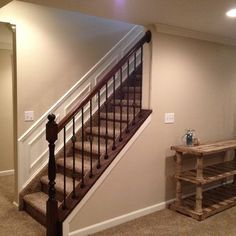 an empty room with stairs leading up to the second floor and a table on the other side