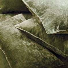 three pillows stacked on top of each other in front of a bed with brown sheets