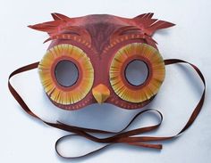 an owl mask is shown on a white surface with a brown ribbon around it's neck