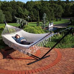 a man laying in a white hammock on top of a red brick walkway