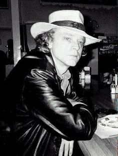 black and white photograph of a man wearing a hat at a bar with his arms crossed