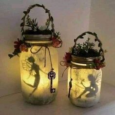 two mason jars with flowers and fairy silhouettes on them