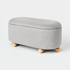 a grey ottoman sitting on top of a white floor next to a wooden foot rest