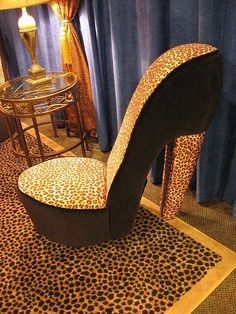 a leopard print chair sitting on top of a rug in front of a table with a lamp