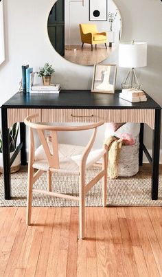 a desk with a mirror, chair and pictures on the wall in front of it