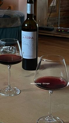 two glasses of wine sitting on top of a table next to a bottle of wine