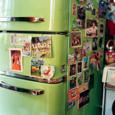 a green refrigerator covered in pictures and magnets next to a stove with a microwave