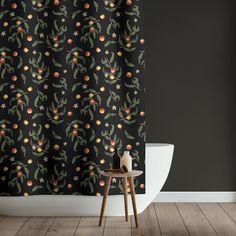 a black shower curtain with oranges and stars on it next to a white toilet