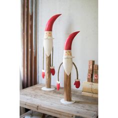 three red and white wooden gnomes on top of a table