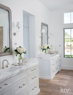 a white bathroom with marble counter tops and double sinks