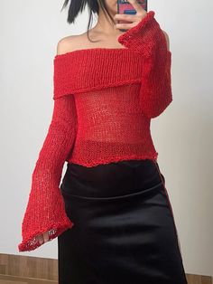 a woman taking a selfie with her cell phone wearing a red sweater and black skirt