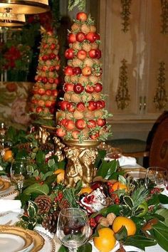 an elaborately decorated table with fruit and greenery on it, including oranges