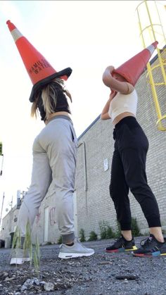 two people with hats on their heads standing in front of a brick wall and building