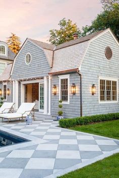 a house with a pool in front of it and some lawn chairs around the pool